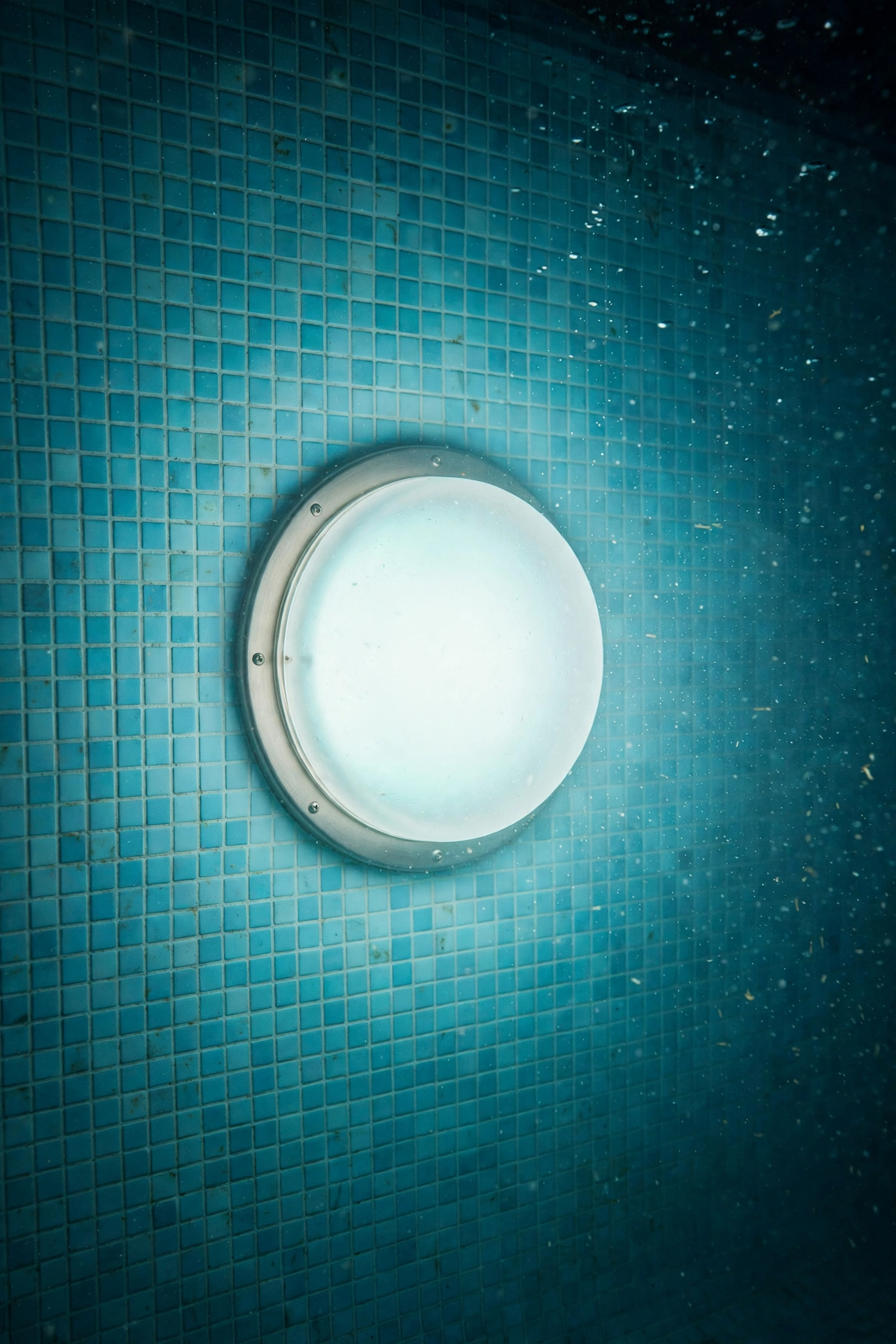 Pool underwater light with frosted lens cover casting a soft diffused glow through the water