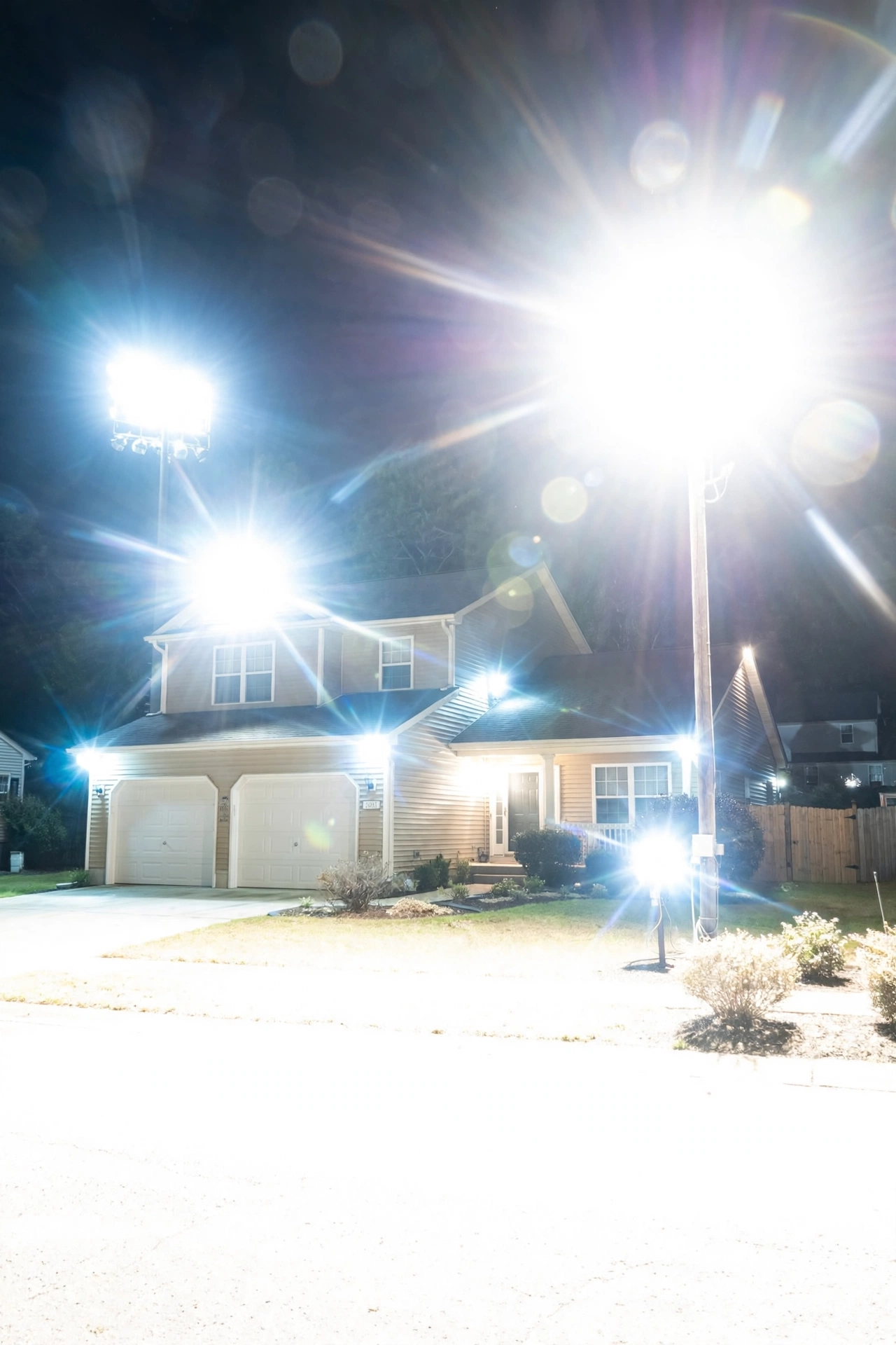 Overly bright mismatched outdoor lights causing glare on a suburban home at night as an example of wasteful lighting